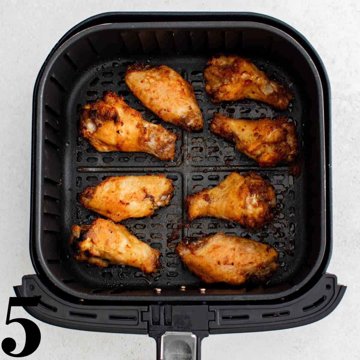 An air fryer basket full of chicken wings.