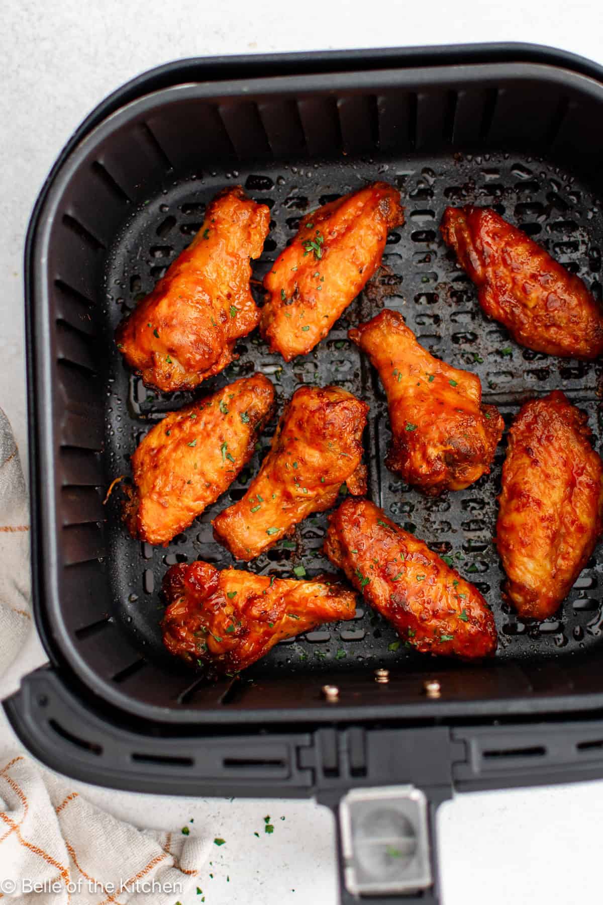 Buffalo wings in an air fryer basket.