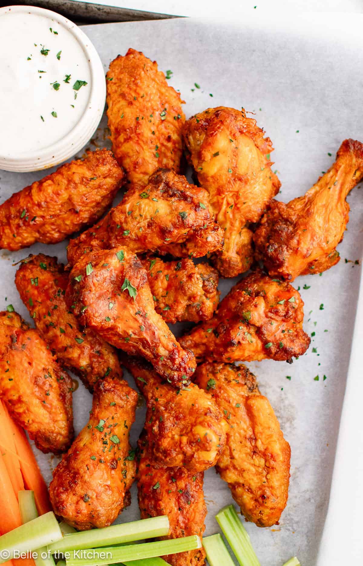 Buffalo wings on a tray with a bowl of ranch, carrots, and celery sticks.