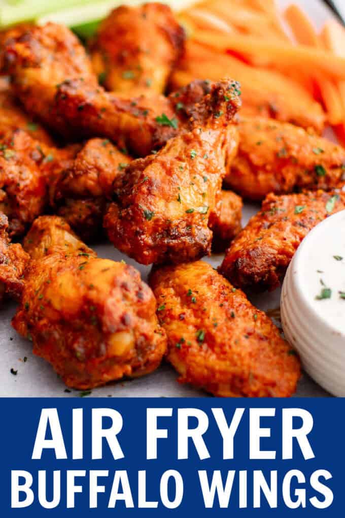 Buffalo wings on a tray with a bowl of ranch, carrots, and celery sticks.