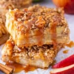 Two slices of apple pie bars stacked with caramel drizzle on top.
