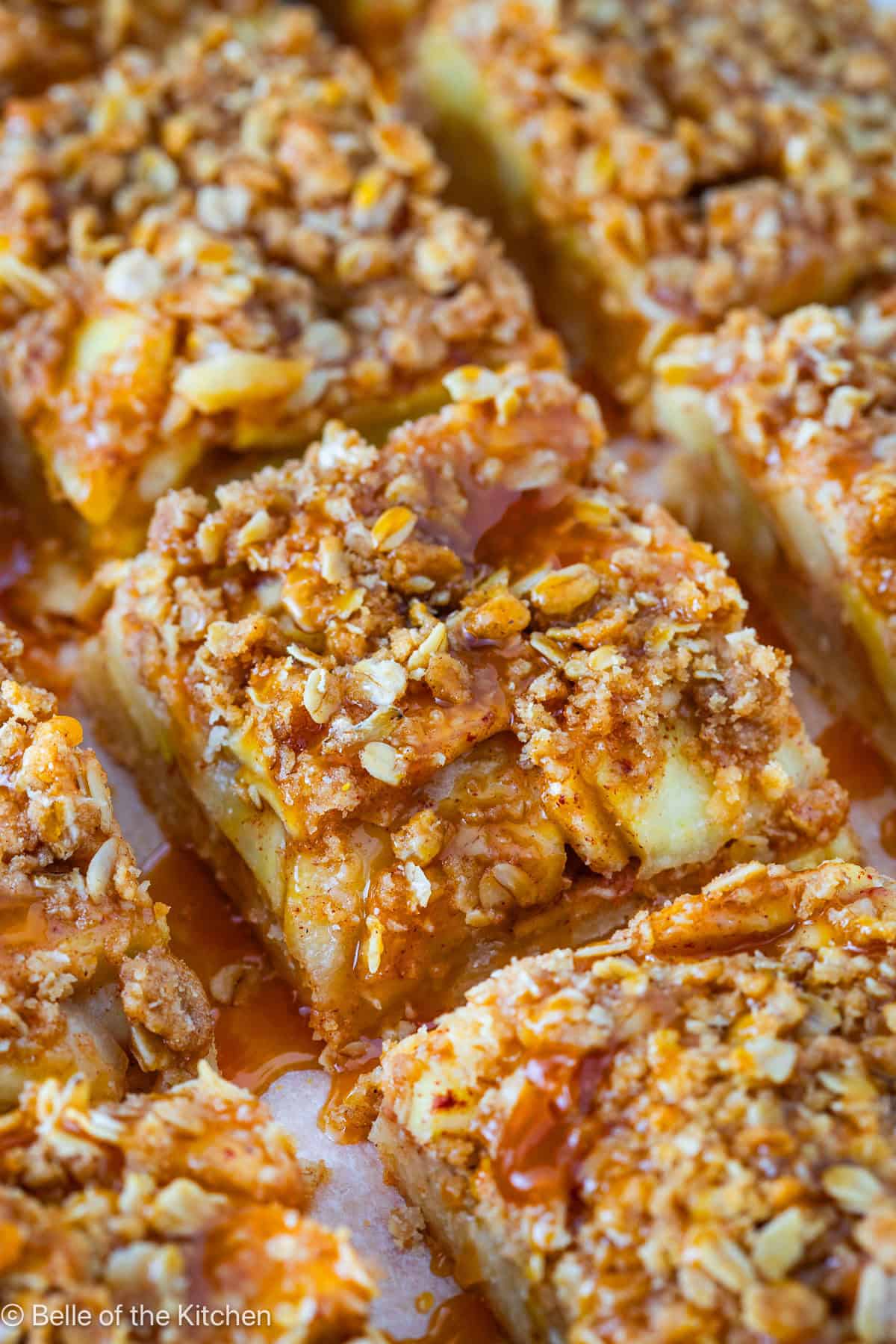 Slices of apple pie bars with caramel on top.