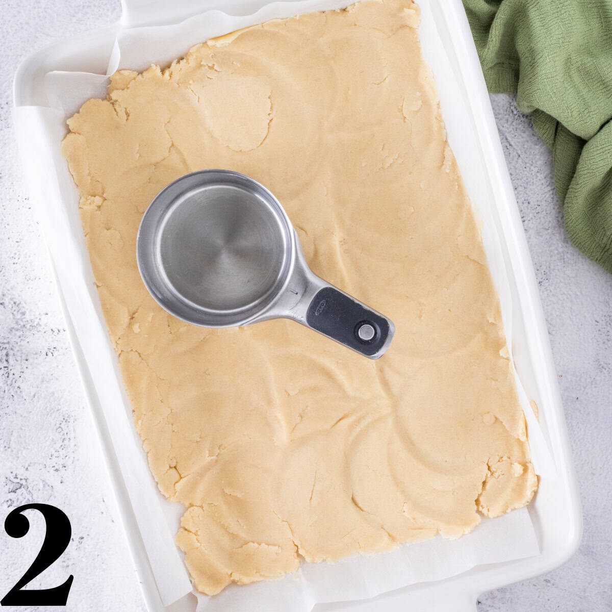 A white baking dish with dough in the bottom.