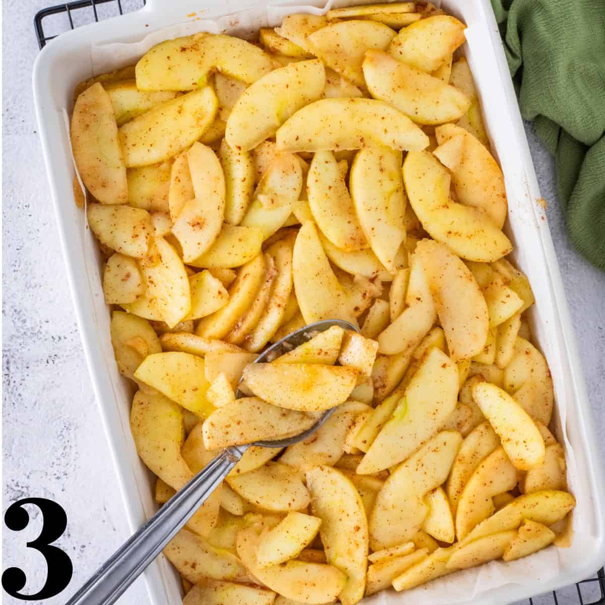 Sliced apples in a white baking dish.