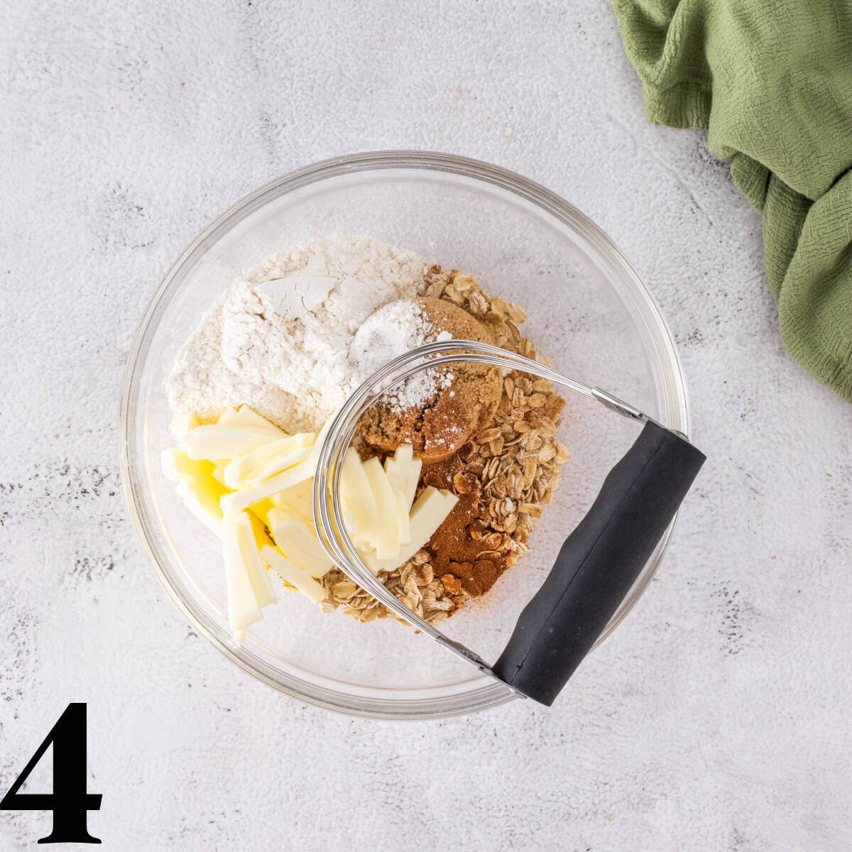 A bowl of butter, sugar, and oats with a pastry blender on top.