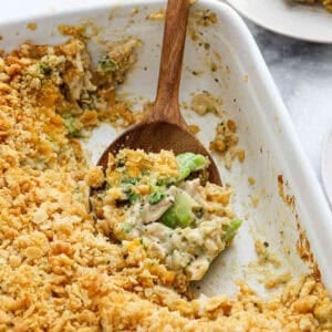 Chicken broccoli rice casserole in a white baking dish with a wooden spoon.