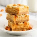 Three pumpkin cheesecake bars stacked on a plate.
