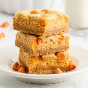 Three pumpkin cheesecake bars stacked on a plate.