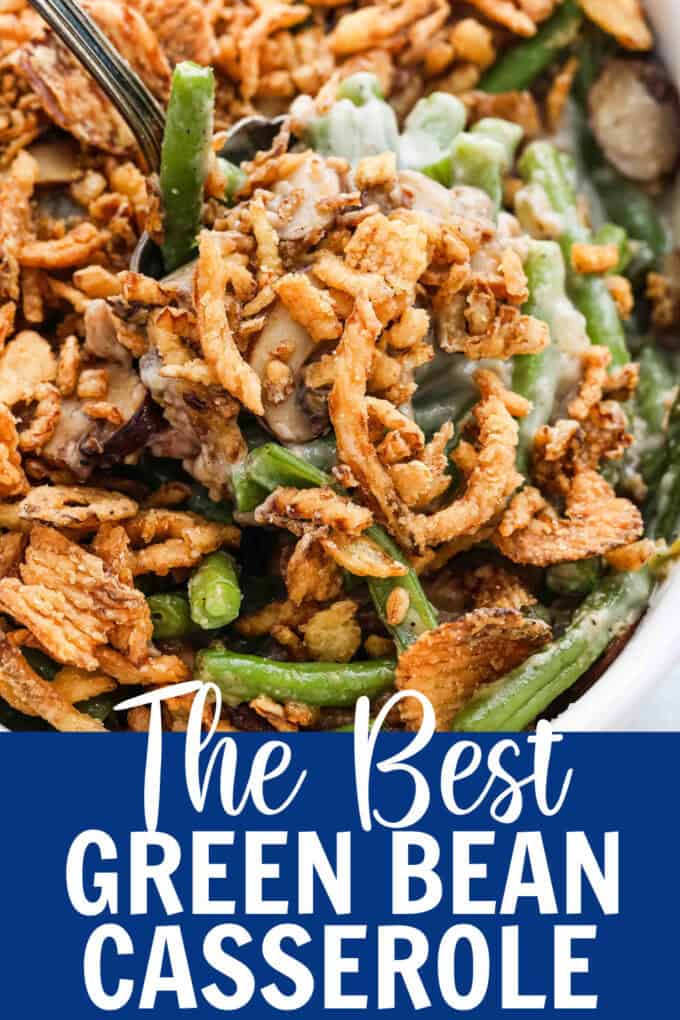 Close up shot of a spoon scooping up green bean casserole from a white baking dish.
