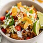 A bowl of taco meat with lettuce, black beans, cheese, tomatoes, and jalapenos.