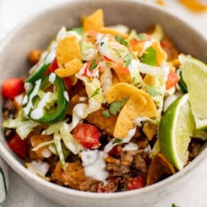 A bowl of taco meat with lettuce, black beans, cheese, tomatoes, and jalapenos.