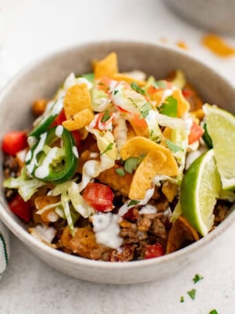 A bowl of taco meat with lettuce, black beans, cheese, tomatoes, and jalapenos.