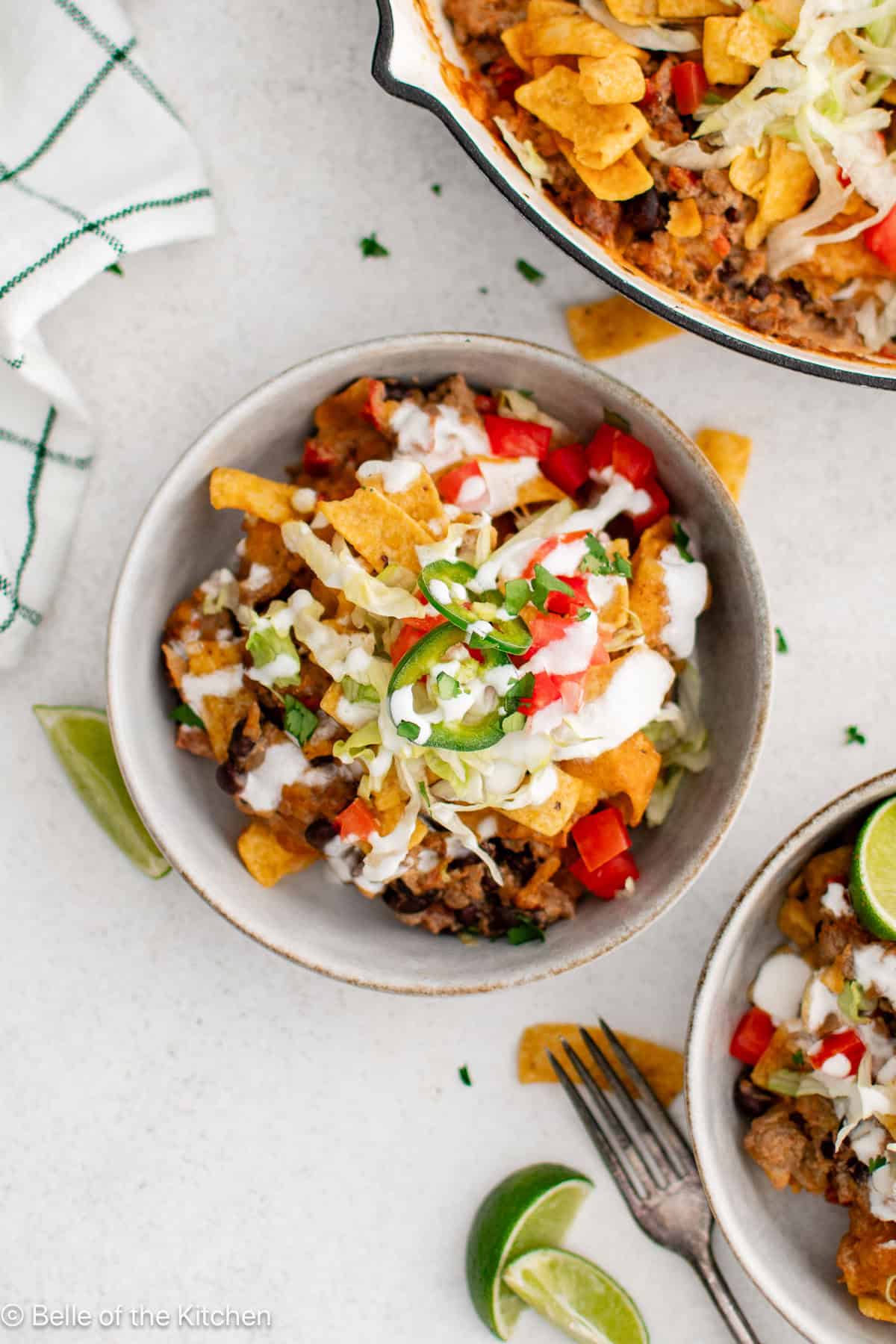 A bowl of taco meat with lettuce, black beans, cheese, tomatoes, and jalapenos.
