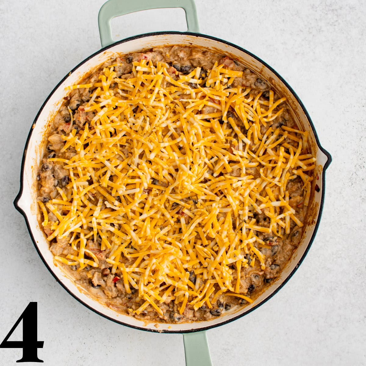 A skillet full of cooked beef with cheese on top.
