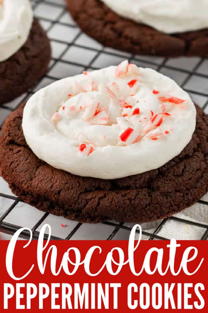 Chocolate cookies topped with frosting and crushed candy canes on a wire rack.