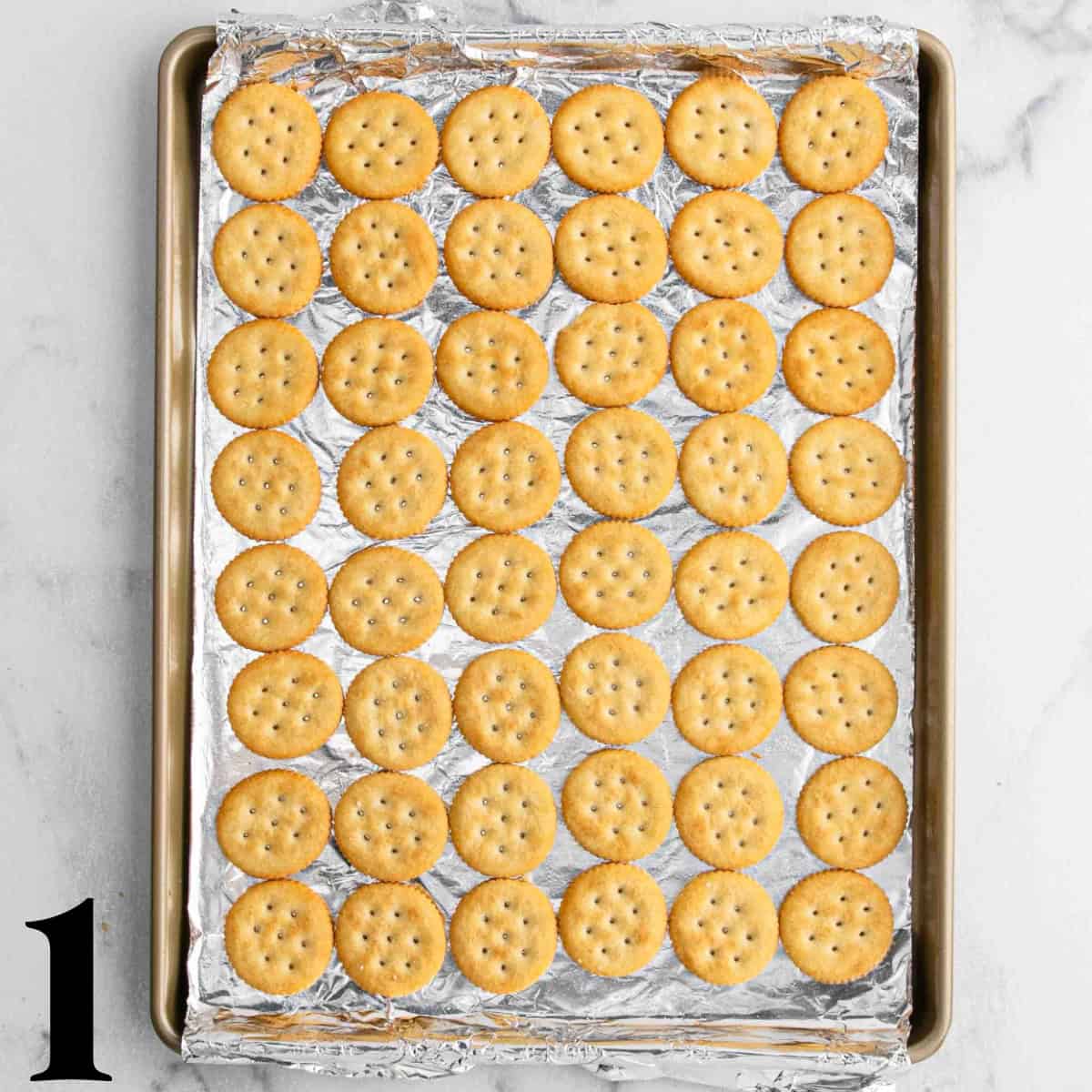 Round crackers laid out on a cookie sheet.