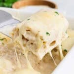 A spatula lifting a lasagna roll from a baking dish.