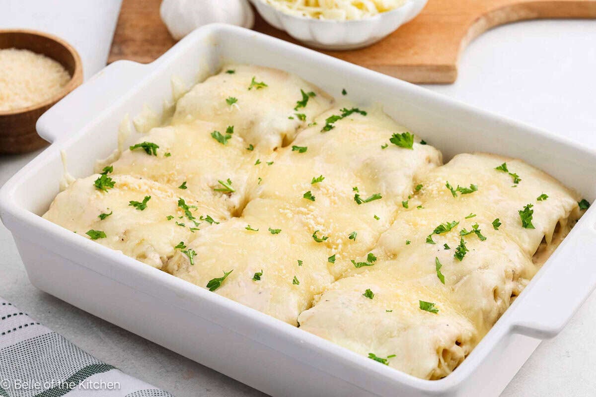 A white casserole dish full of lasagna roll ups.