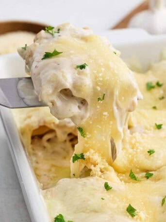A spatula lifting a lasagna roll from a baking dish.