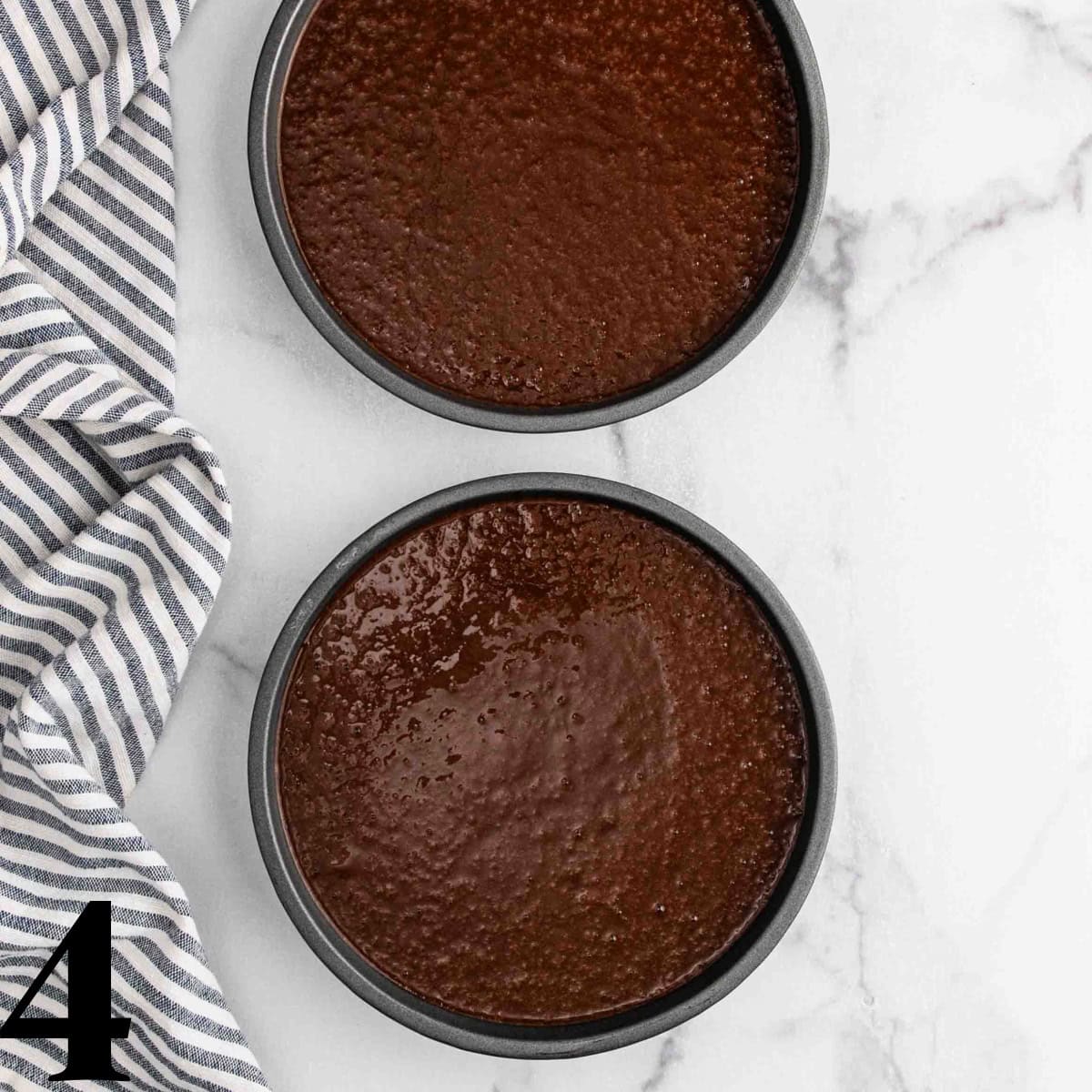 Two round cake pans full of chocolate cake batter.