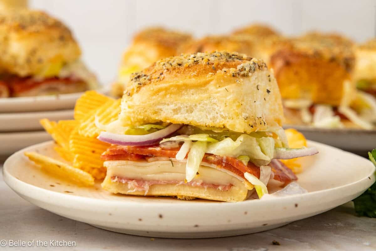 A slider sandwich on a plate with chips.