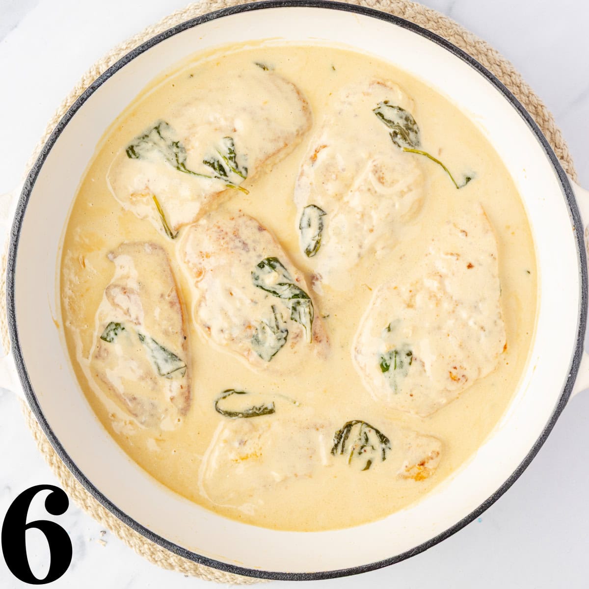 A skillet full of a cream sauce and chicken.