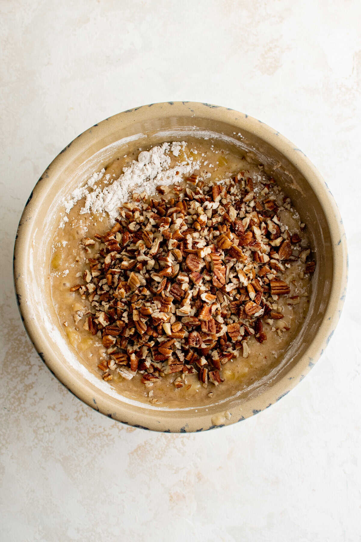 A bowl of cake batter with pecans on top.
