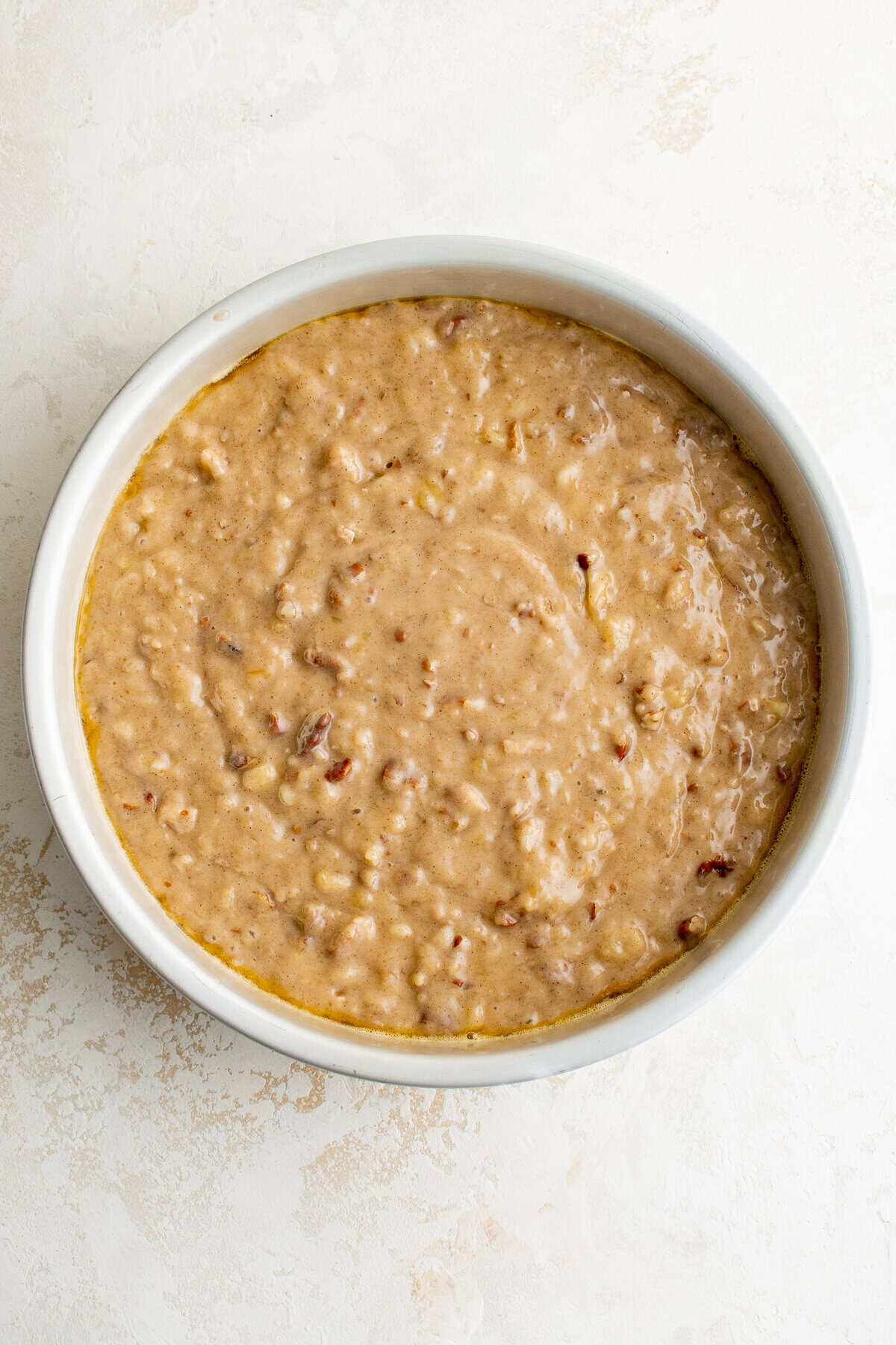 Cake batter in a round cake pan.