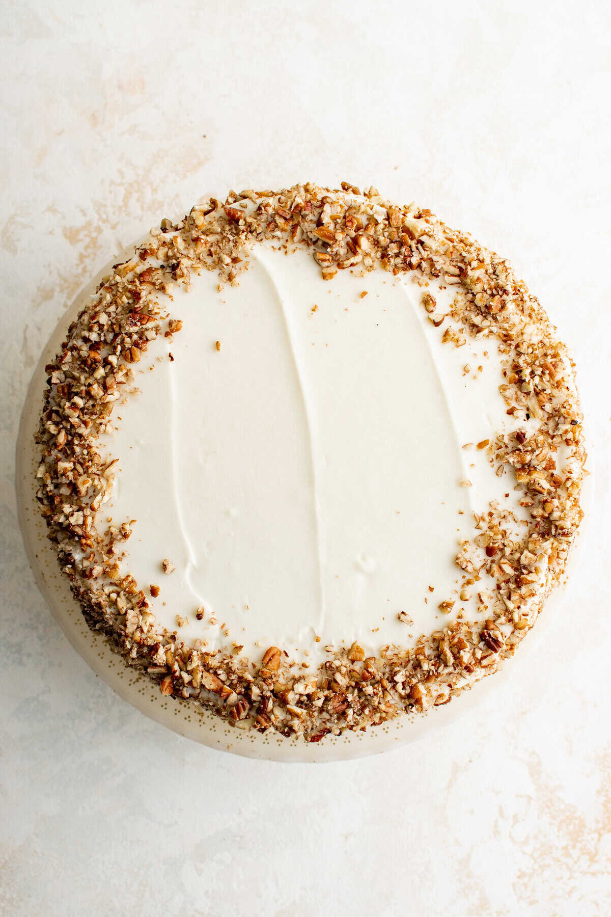 A cake with frosting and pecans on top.