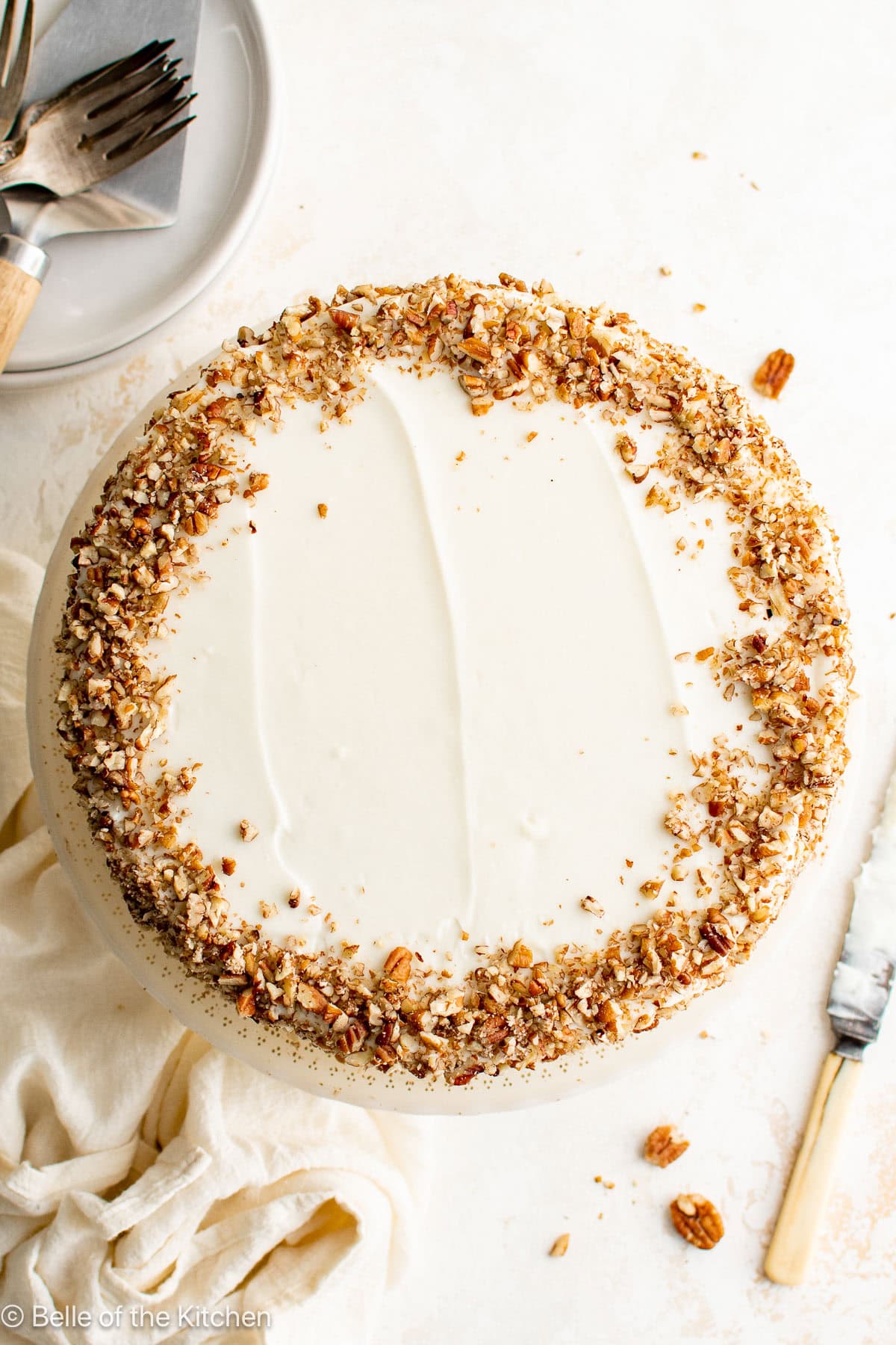 A cake with frosting and pecans on top.