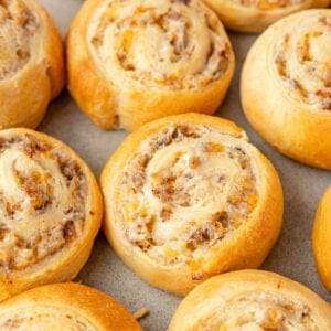 A close up of sausage pinwheels on a cookie sheet.