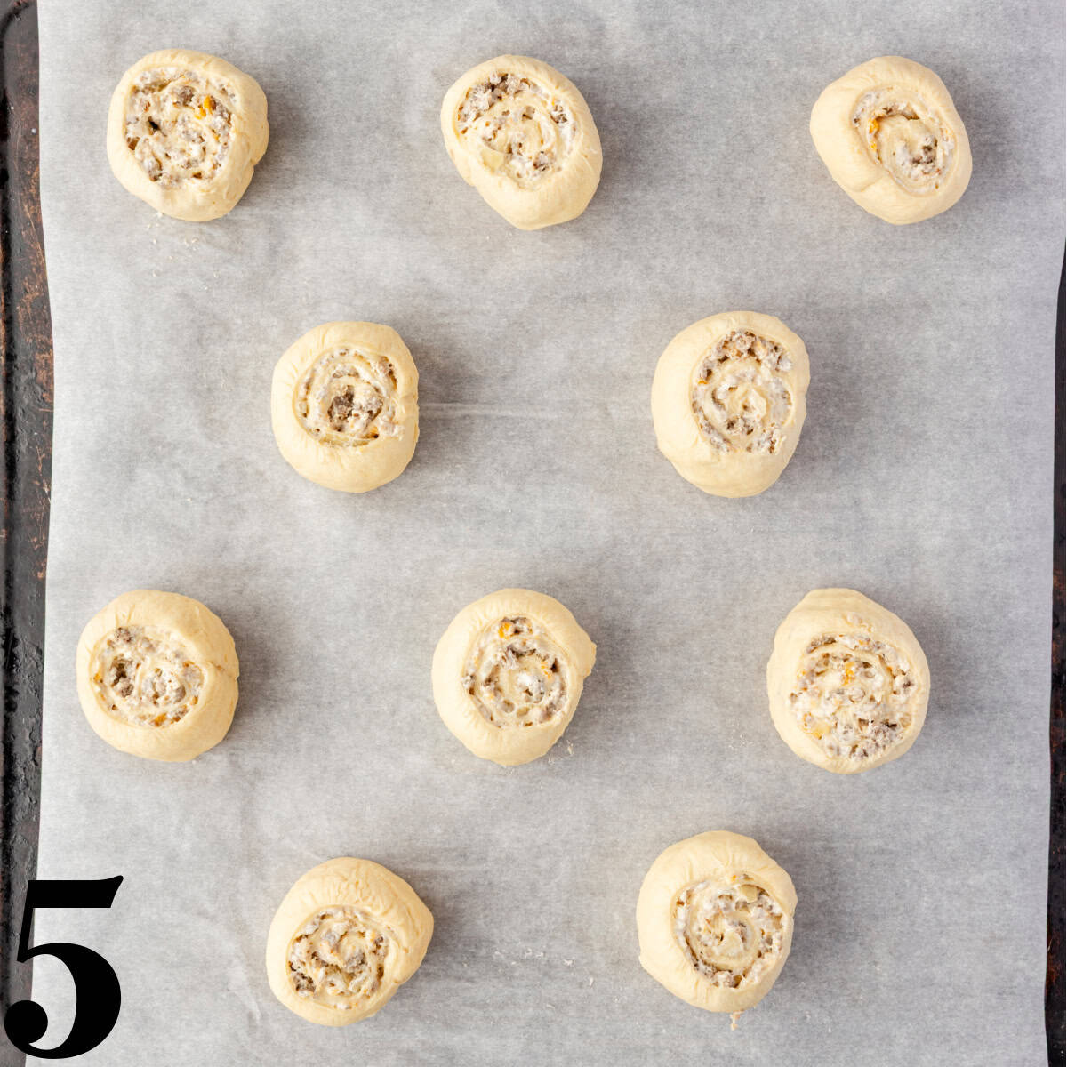 Unbaked sausage pinwheels on a cookie sheet.
