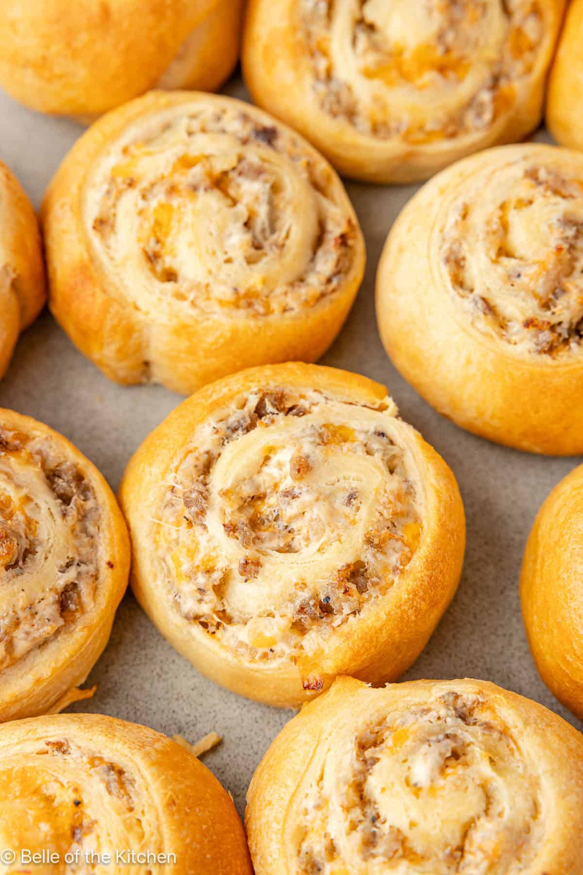 A close up of sausage pinwheels on a cookie sheet.