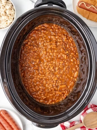 A black crockpot full of baked beans.