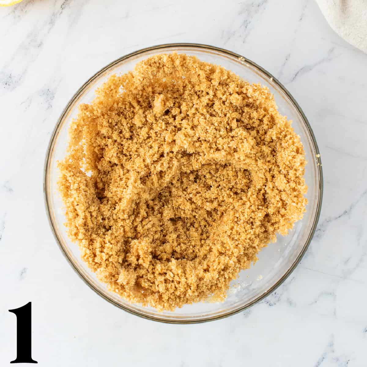A glass bowl of crushed graham cracker crumbs.
