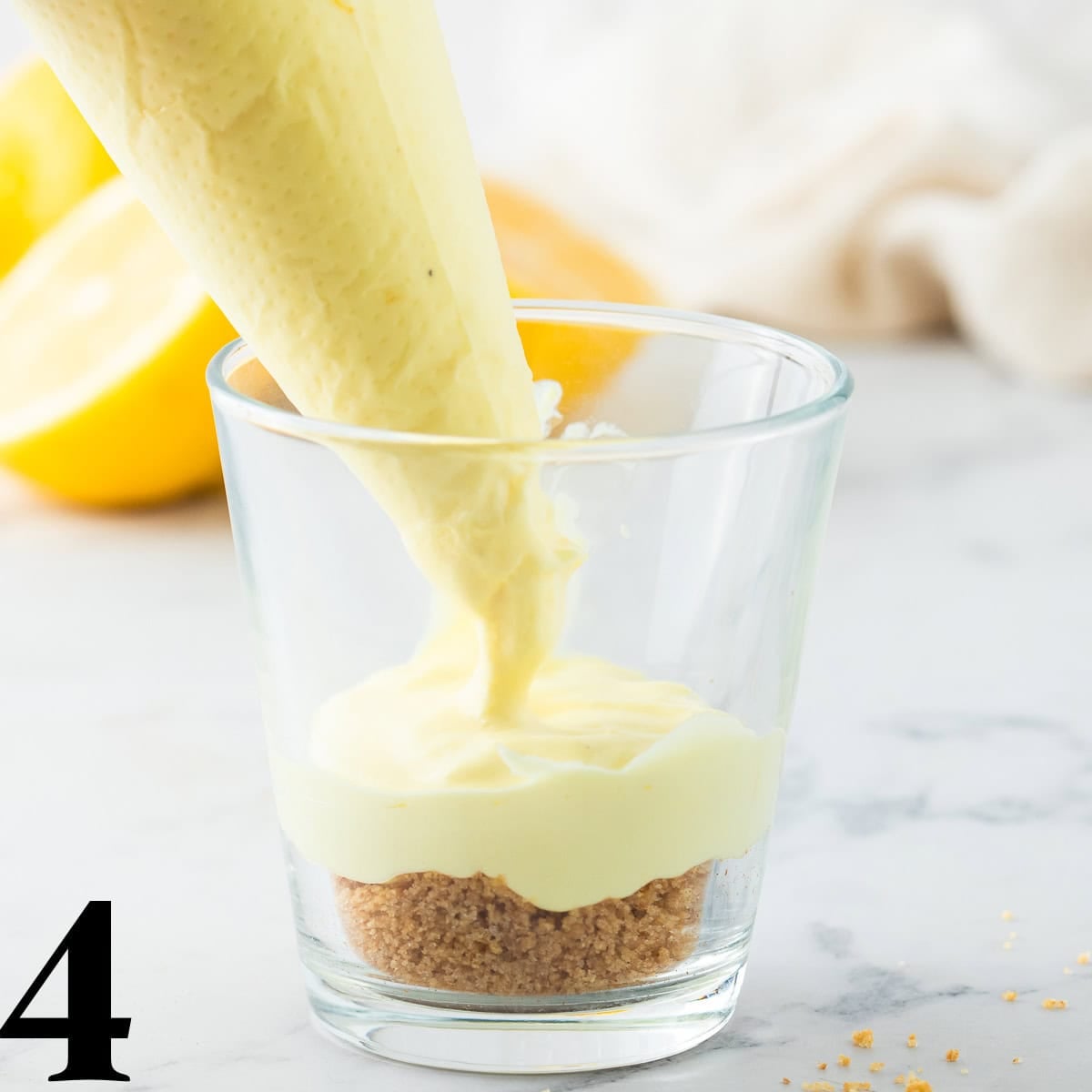 A piping bag adding filling to a dessert cup.