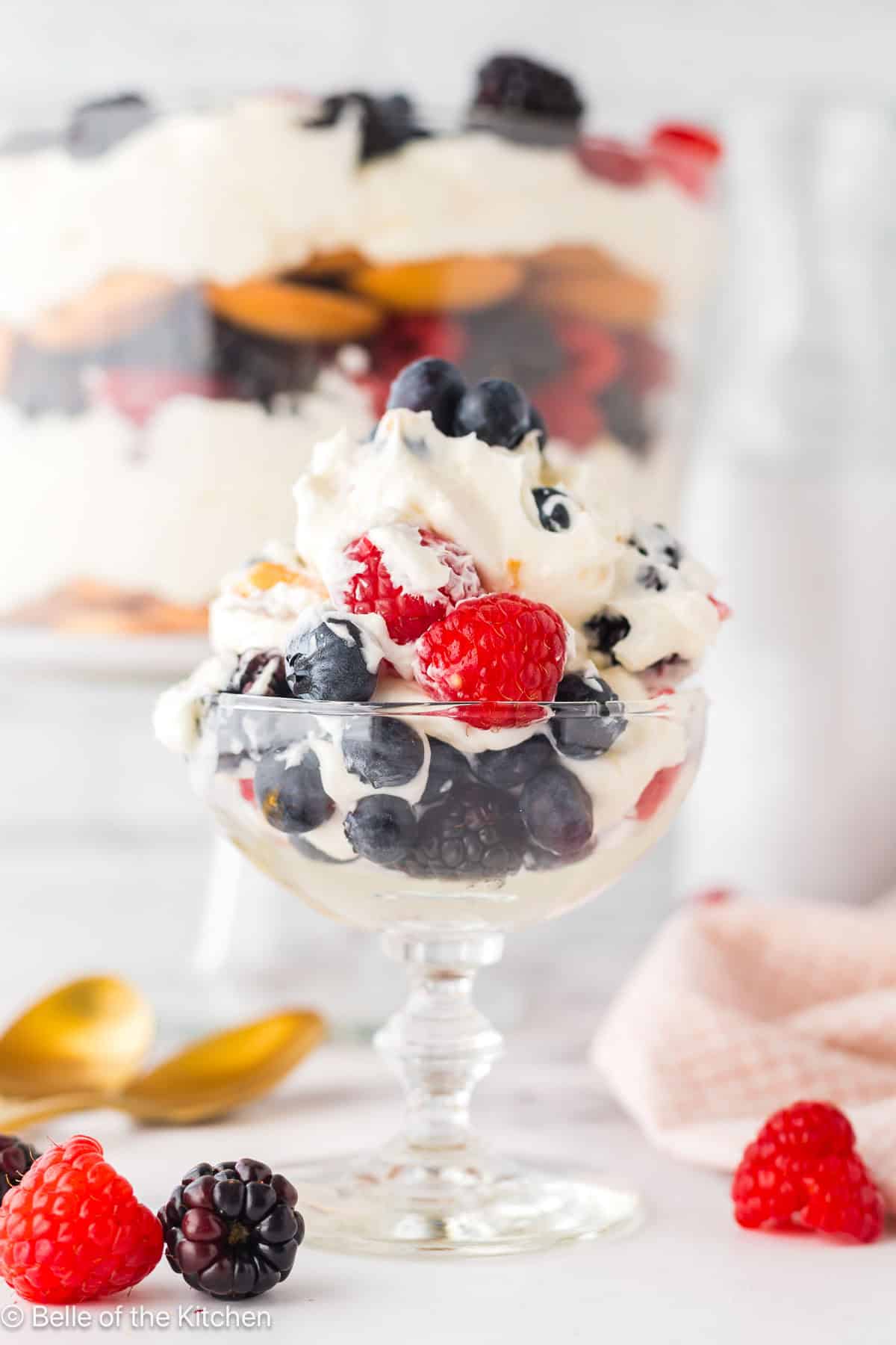 A glass parfait dish full of berries and whipped cream.