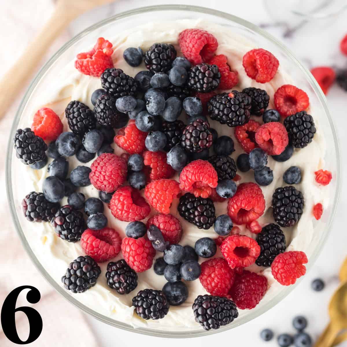 A bowl of mixed berries on top of whipped cream.