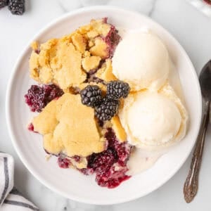 A bowl of blackberry cobbler with vanilla ice cream on top.