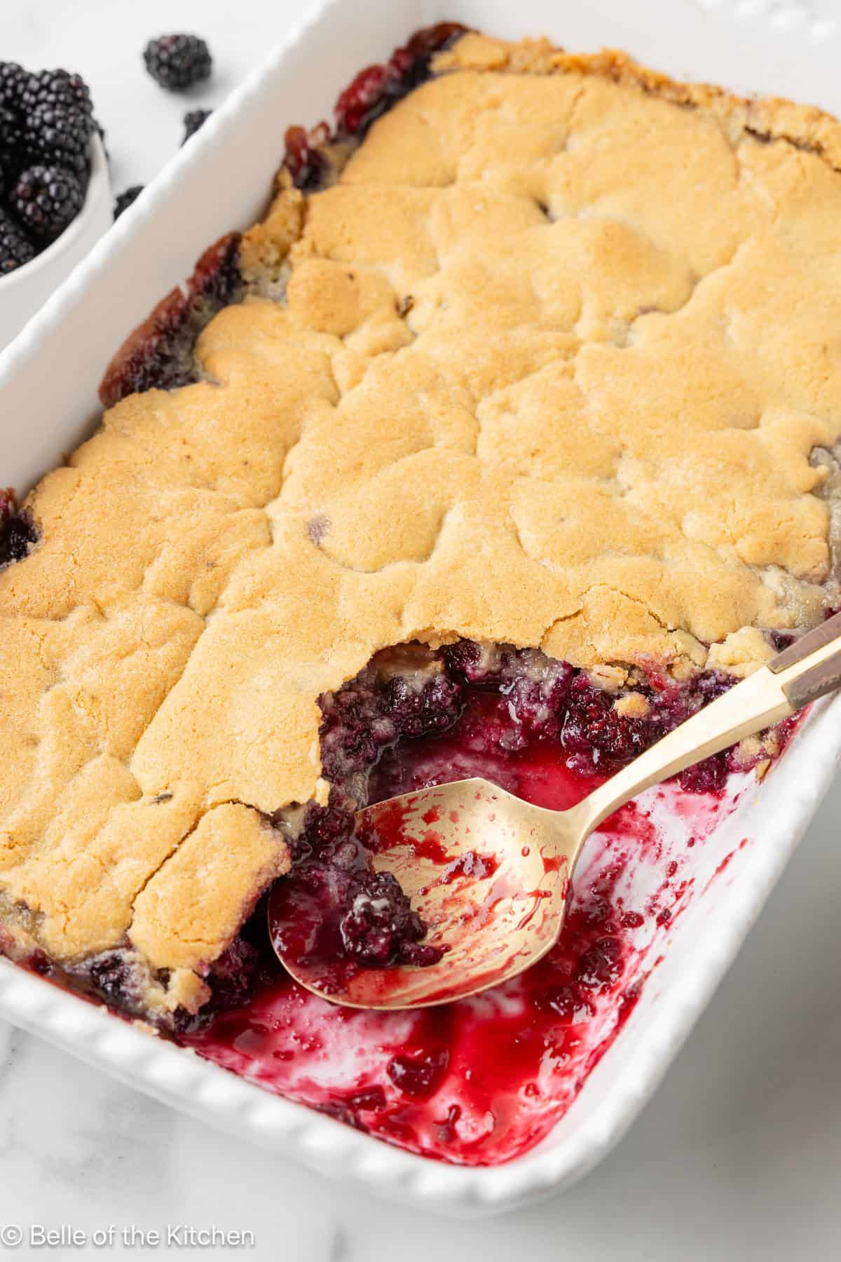 A white baking dish full of blackberry cobbler.