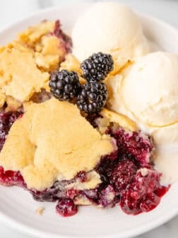 A bowl of blackberry cobbler with vanilla ice cream on top.