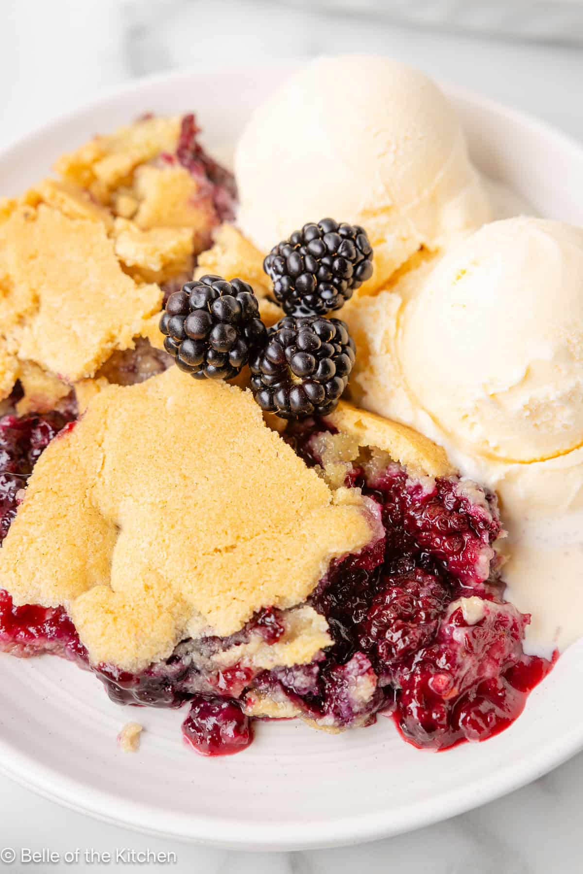 A bowl of blackberry cobbler with vanilla ice cream on top.