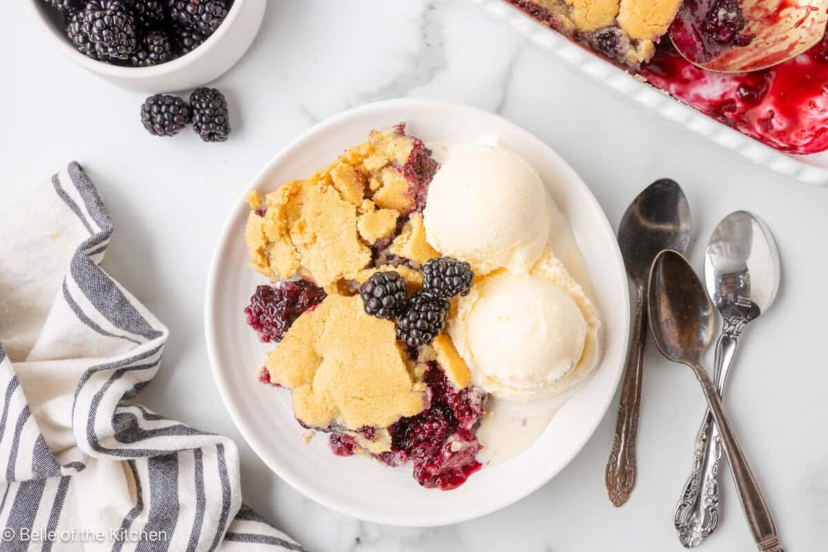 A bowl of blackberry cobbler with vanilla ice cream on top.