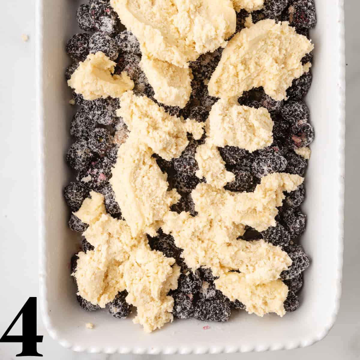 A baking dish full of blackberries topped with cobbler batter.