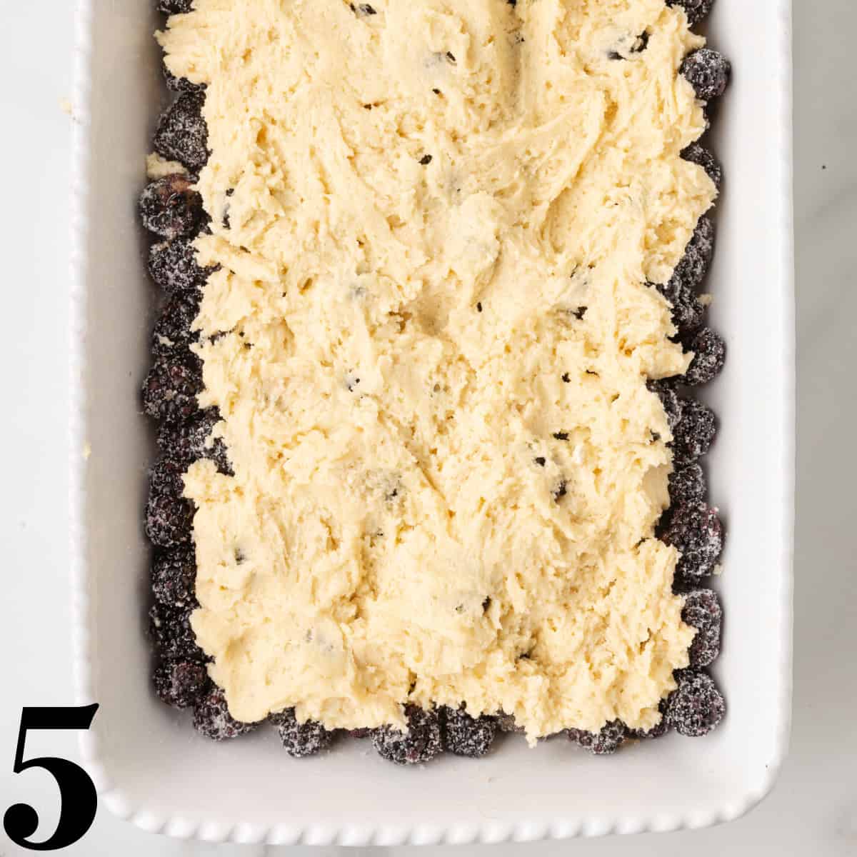 A baking dish full of blackberries topped with cobbler batter.