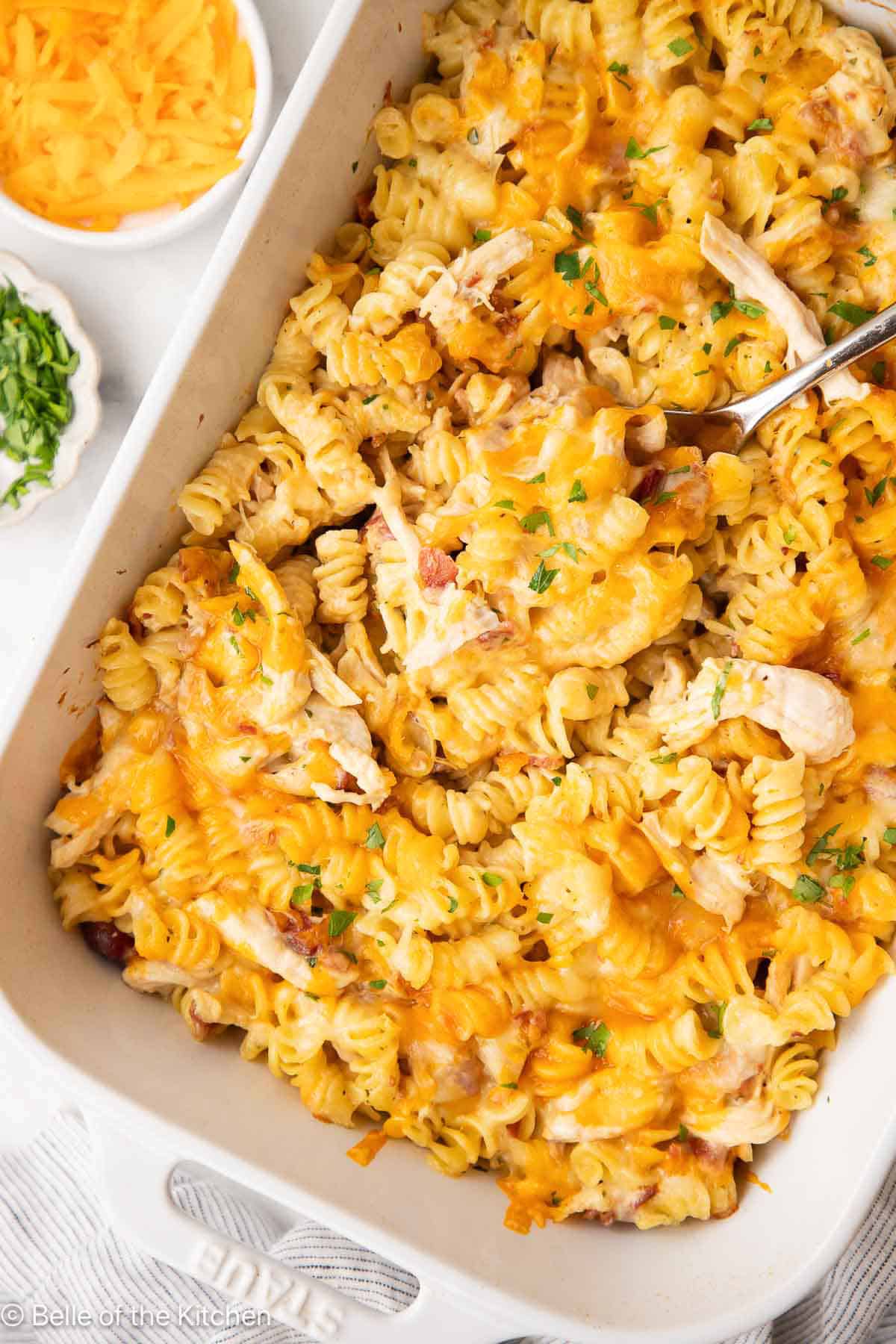 A white baking dish full of pasta, chicken, bacon, and cheese.