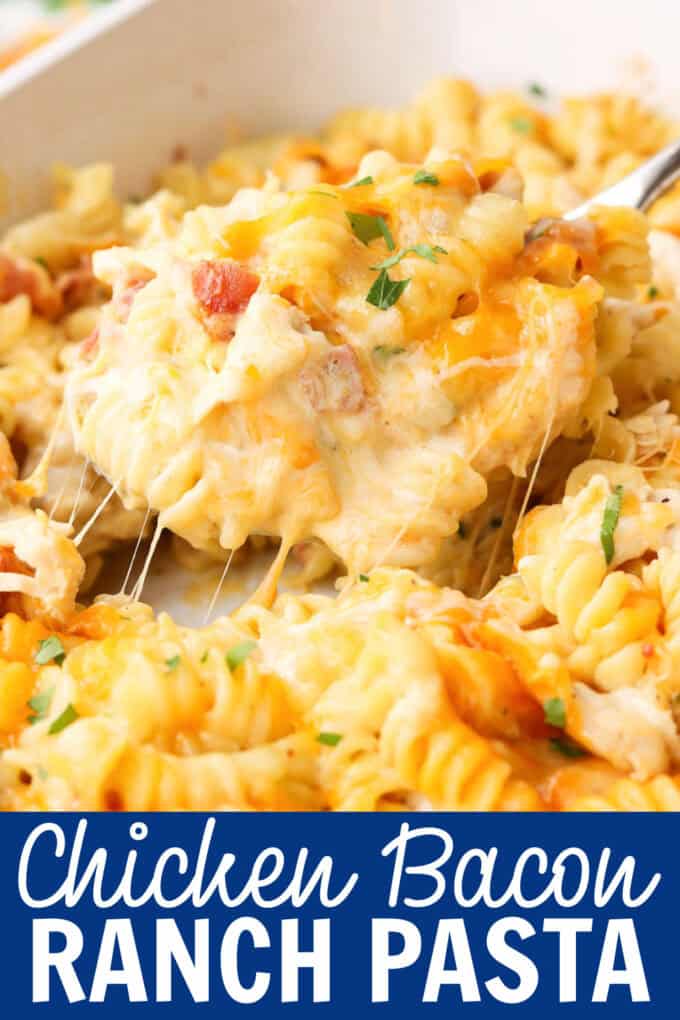 A spoon lifting food from a white baking dish full of pasta, chicken, bacon, and cheese.