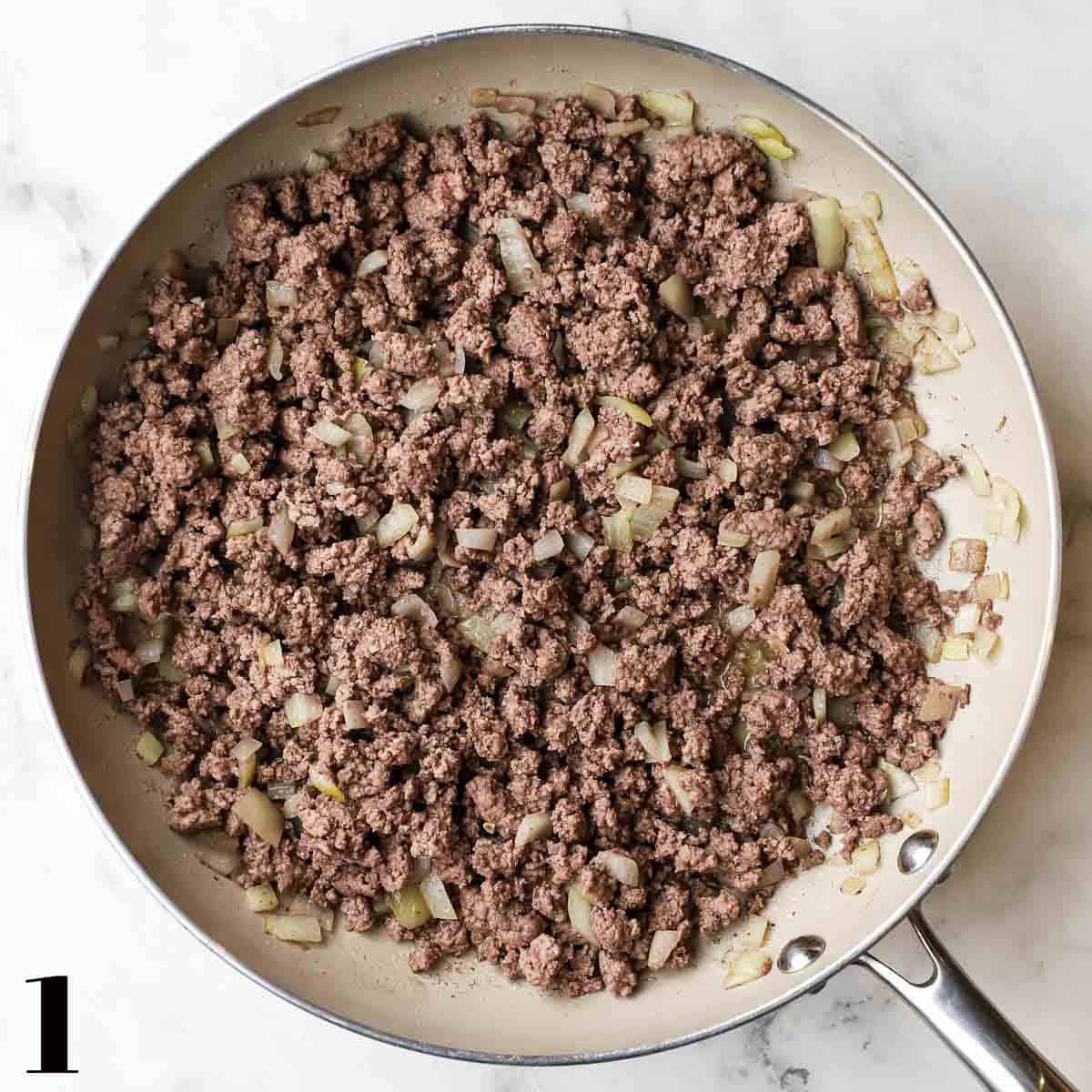A skillet full of cooked ground beef and onions.