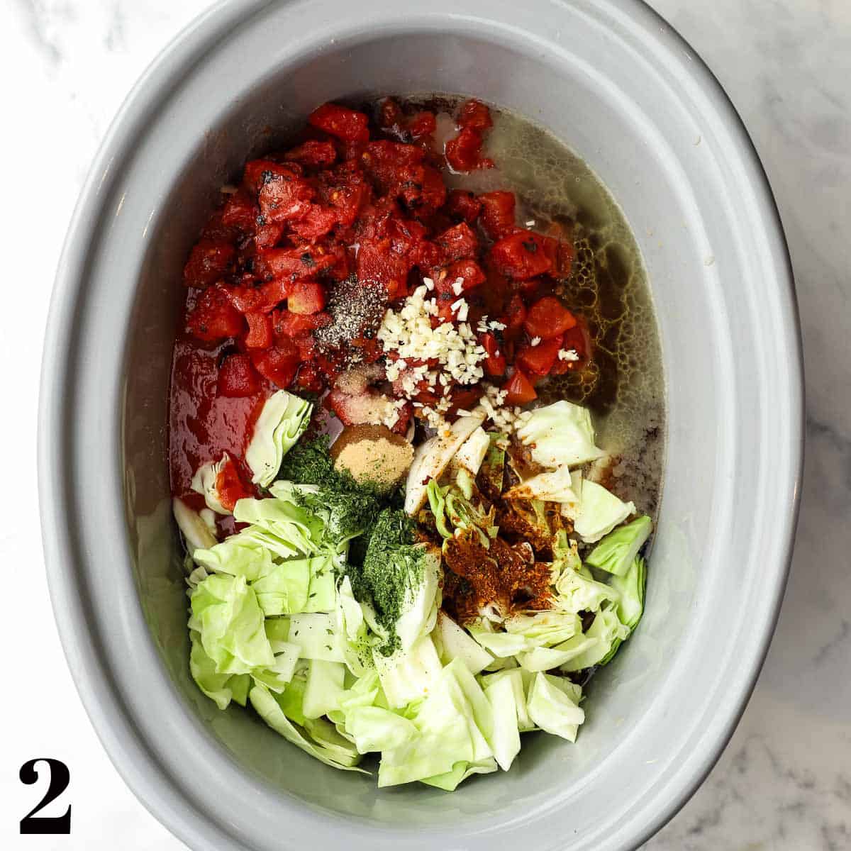 A crockpot full of cabbage, meat, and tomatoes.