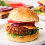 A turkey burger with a bun and toppings on a white plate.